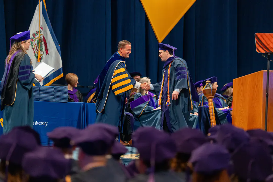 Photo of a WVU Law graduate shaking hands with President Michael T. Benson.