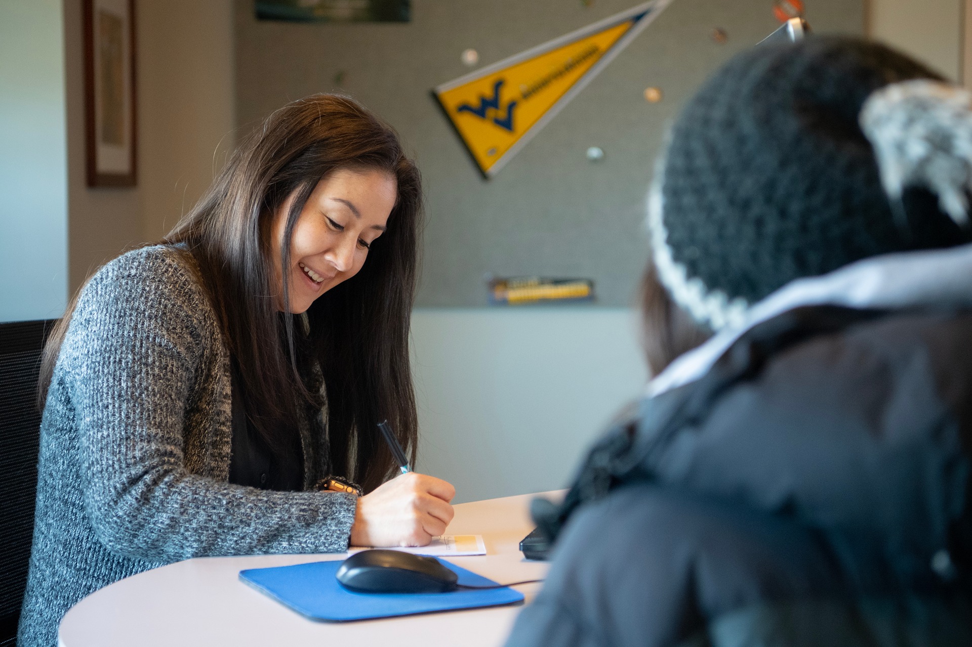 A WVU Hub staff member meeting with a student at their desk.