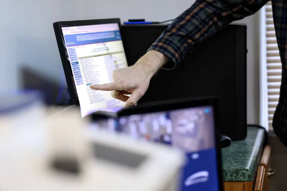 Someone pointing at a computer monitor.