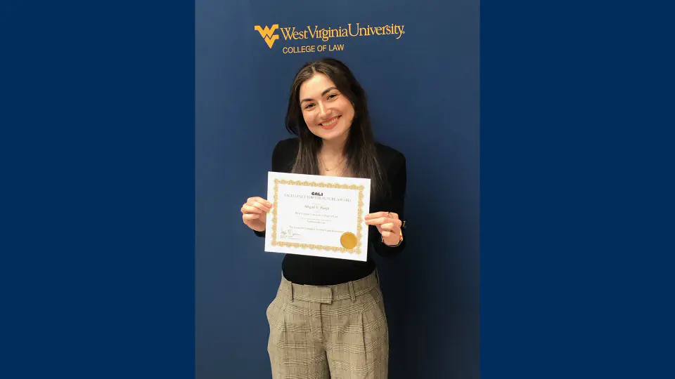 Abigail holding an award certificate she received for "Excellence for the Future" the College of Law.