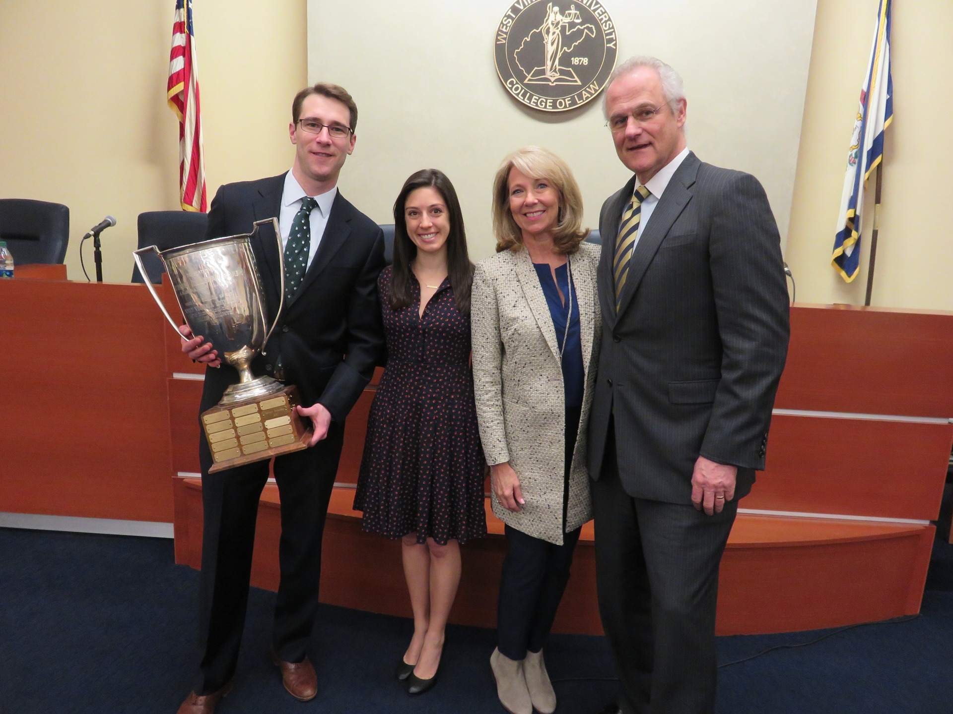 Photo of WVU Law student Chase Farmer holding the Baker Cup beside his wife Katie, mother, and father Steve.