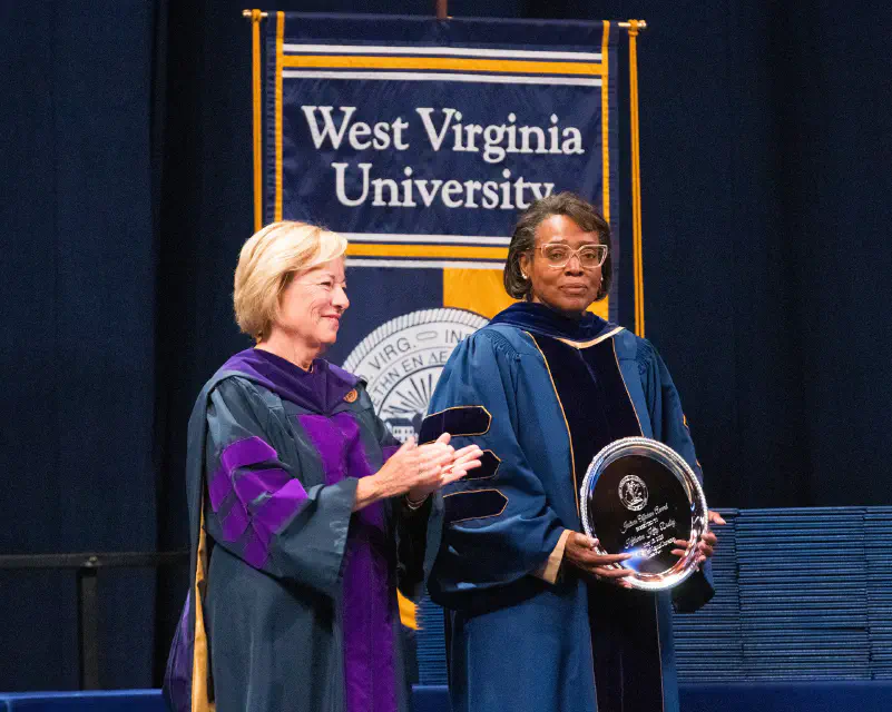 Photo of Dr. Elizabeth Dooley standing with Interim Dean Susan Brewer, holding an award for her sister, Kitty Dooley.