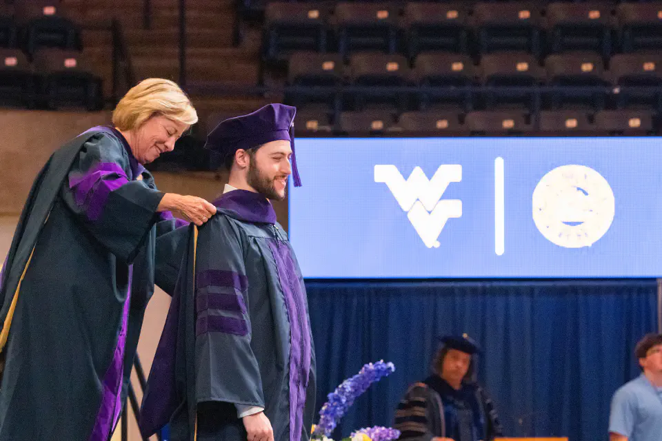 Photo of a WVU Law graduate receiving his hood from Interim Dean Susan Brewer.
