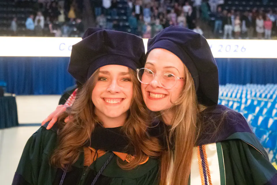 Photo of two WVU Law graduates posing together in graduation regalia.