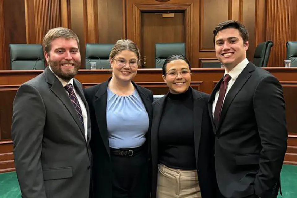 Four students competing in Moot Court stand in a court room.