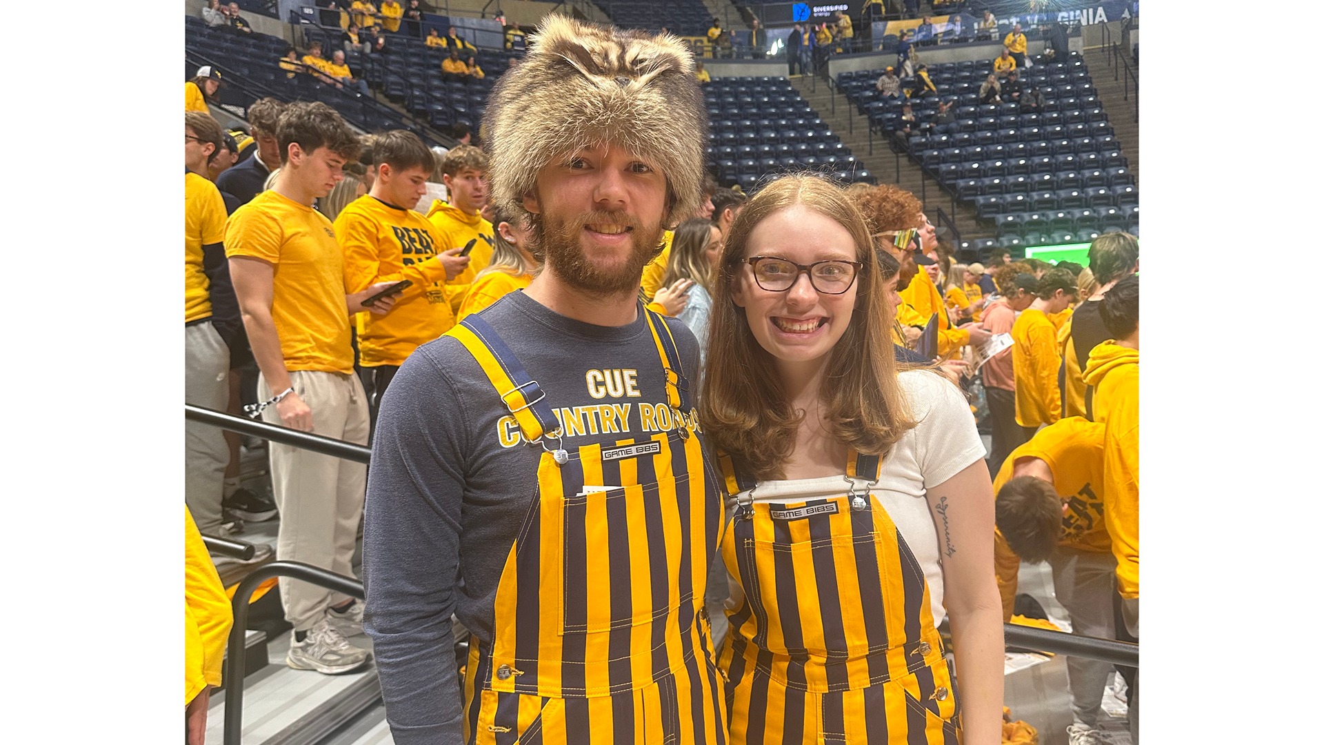 Photo of Parker Stout and Kayla Brown standing together in the WVU Coliseum, dressed in game day gear.