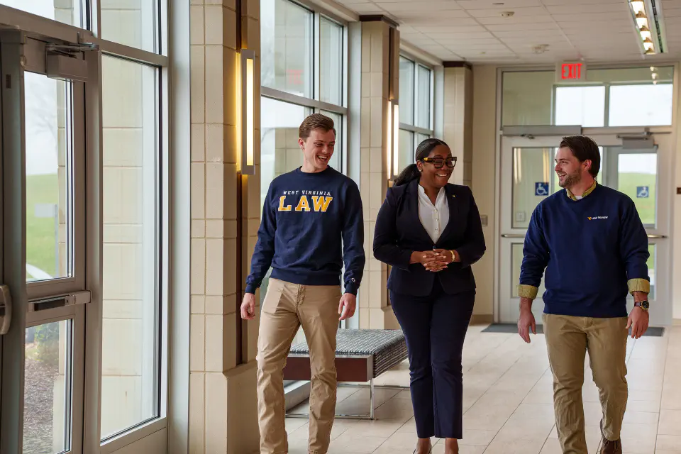 Three Law students walk in a hallway.